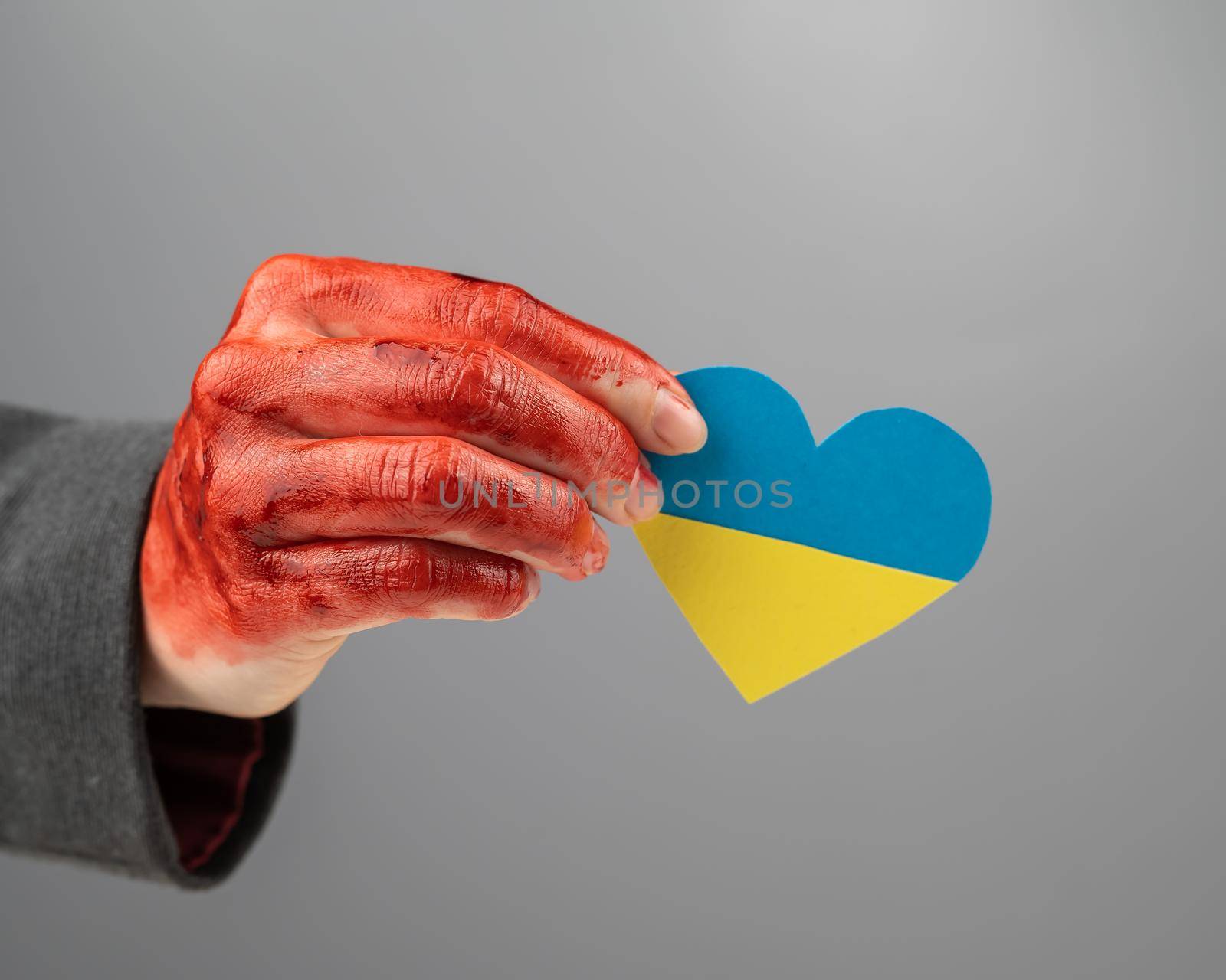 Woman with hands covered in blood holding a heart with the flag of ukraine on a white background. by mrwed54