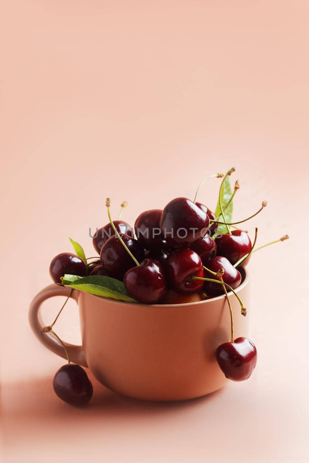 Fresh, ripe cherries in a ceramic mug on a beige background. copy space