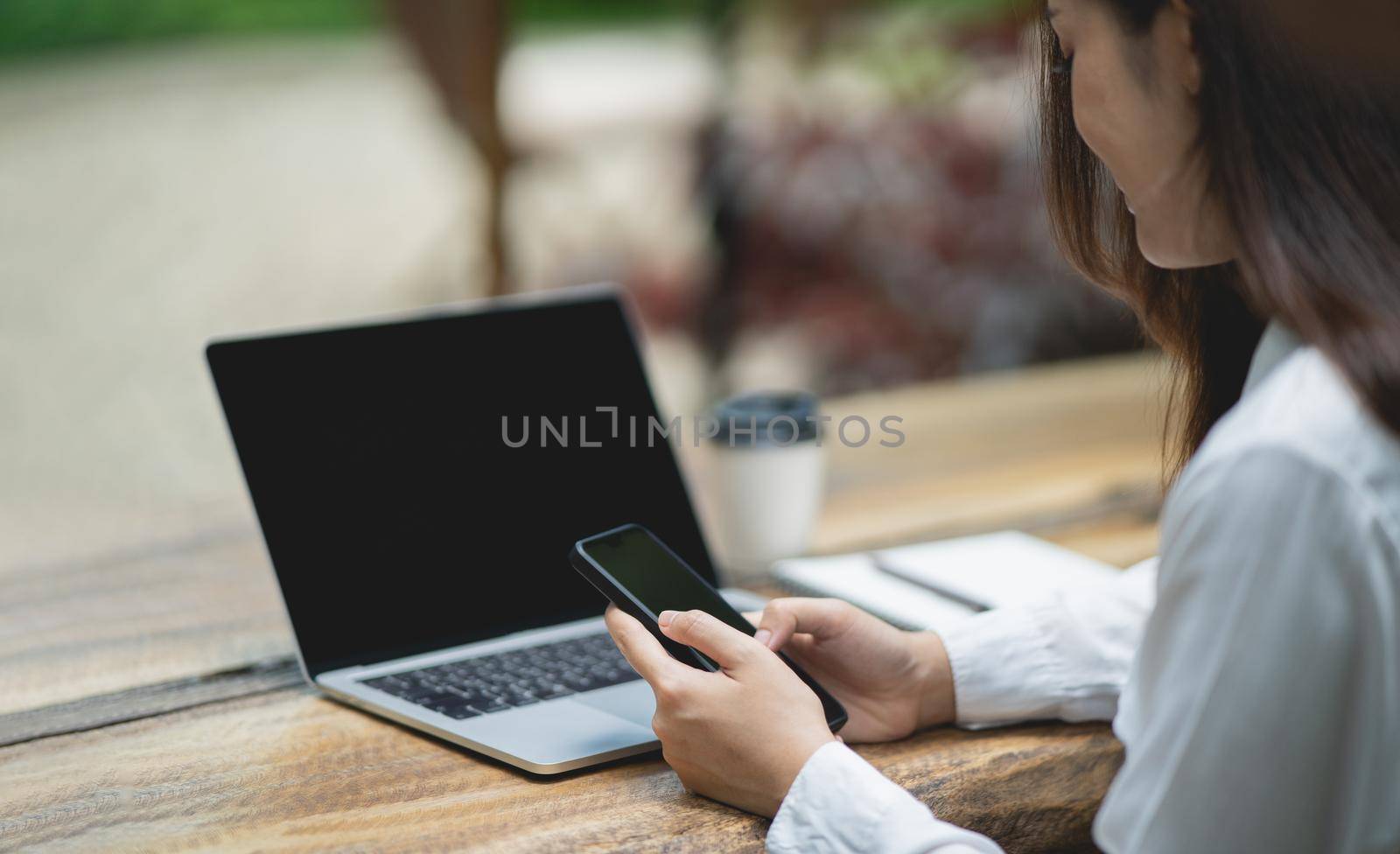 woman hold mobile phone text or message. Businesswoman use smartphone to browse web, working laptop, trade stocks. by Wmpix