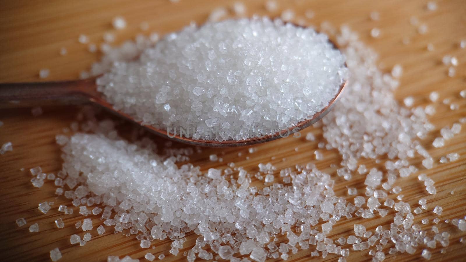 Macrophotography.A spoon with sugar on a wooden table. Close-up of sugar crystals.Background or texture