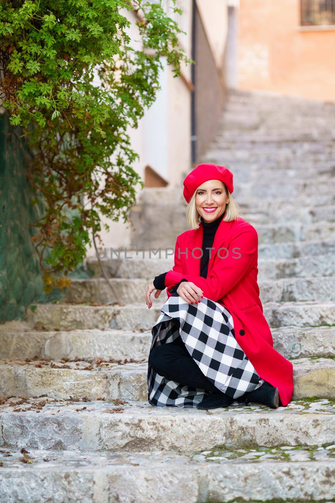 Happy graceful lady sitting on stairs on street by javiindy