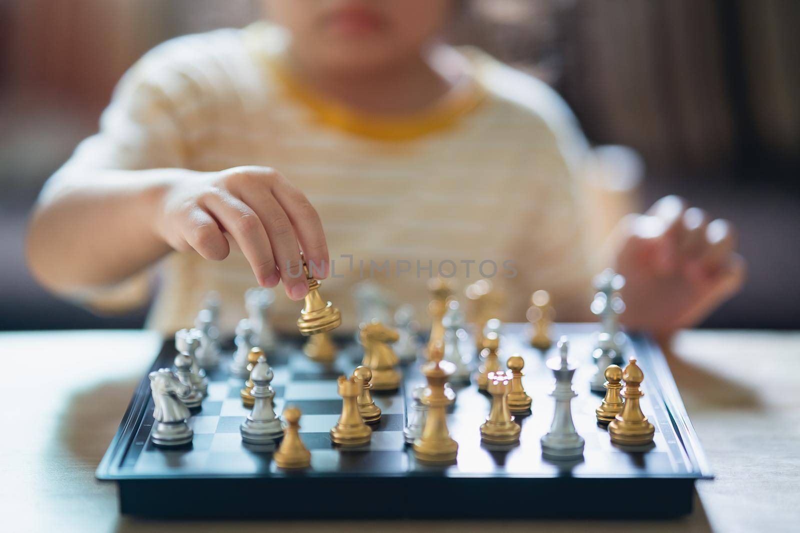 Little asian baby playing chess in the living room at home.Smart kid.fashion children. Little genius Child. Intelligent game.Chessboard. Baby activity concept. by Wmpix
