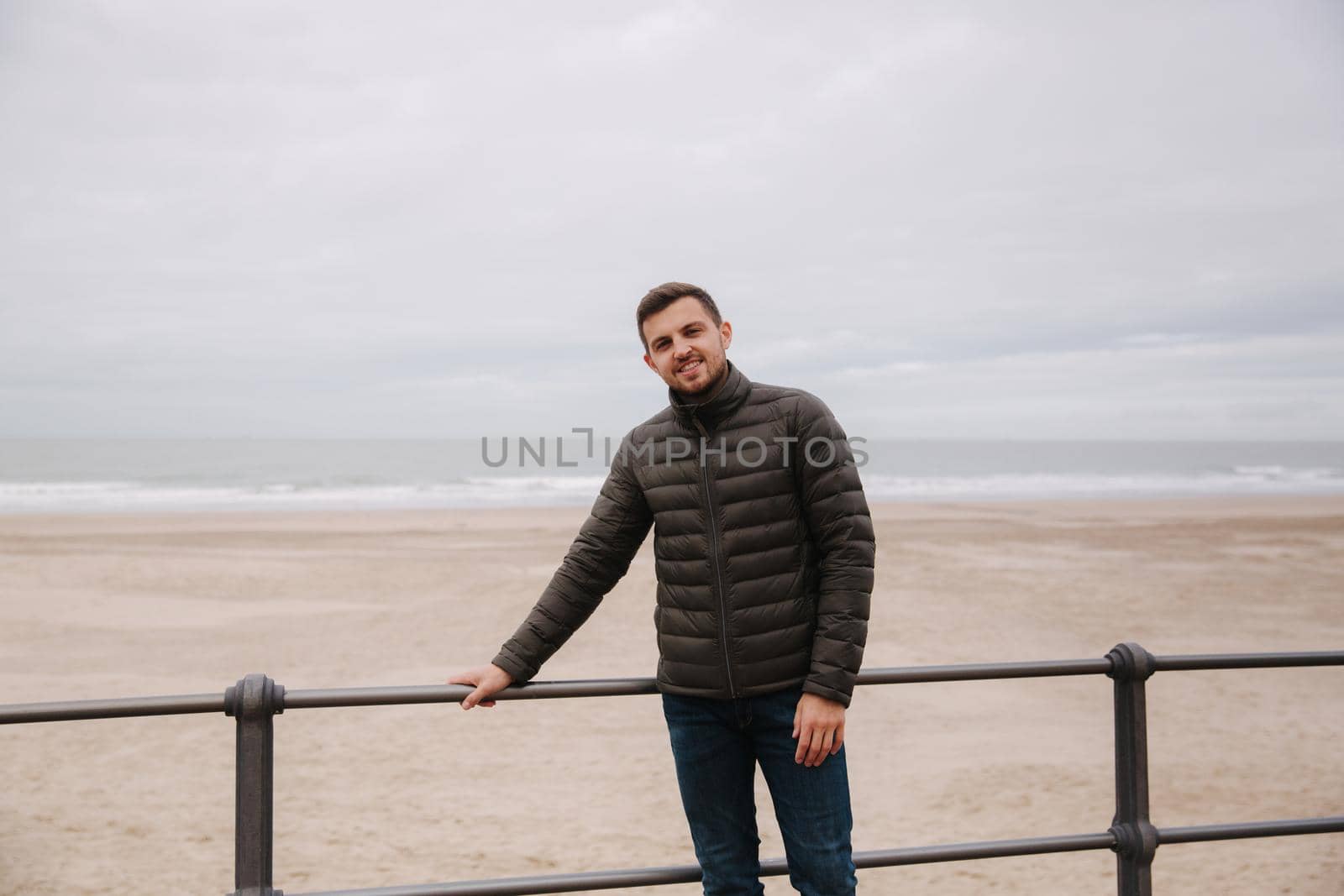 Handsome man standing in front of North Sea. Stylish man in khaki jacket.