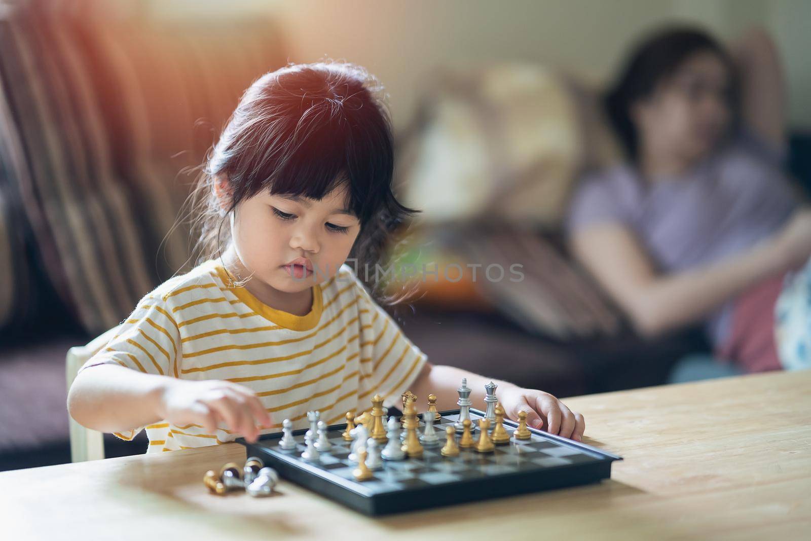 Little asian baby playing chess in the living room at home.Smart kid.fashion children. Little genius Child. Intelligent game.Chessboard. Baby activity concept.