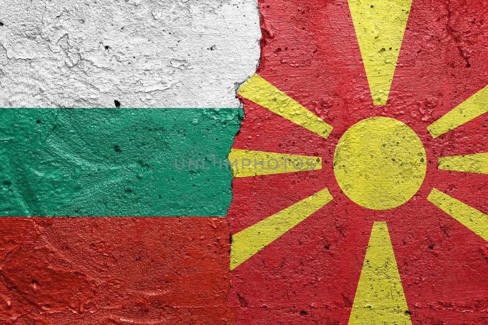 Bulgaria and North Macedonia - Cracked concrete wall painted with a Bulgarian flag on the left and a Macedonian flag on the right stock photo by adamr