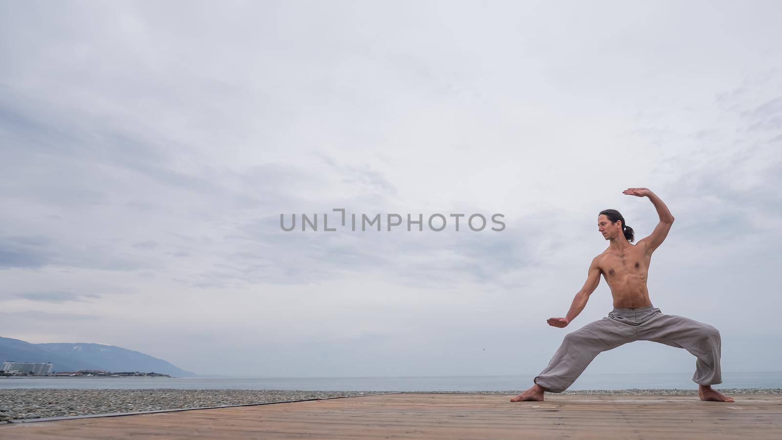 Caucasian man with naked torso practicing wushu on the seashore. by mrwed54