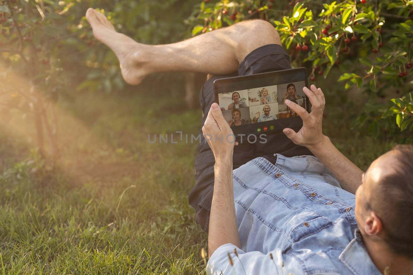 Young man in the garden in summer on the laptop computer while chatting online as a freelancer. by Andelov13