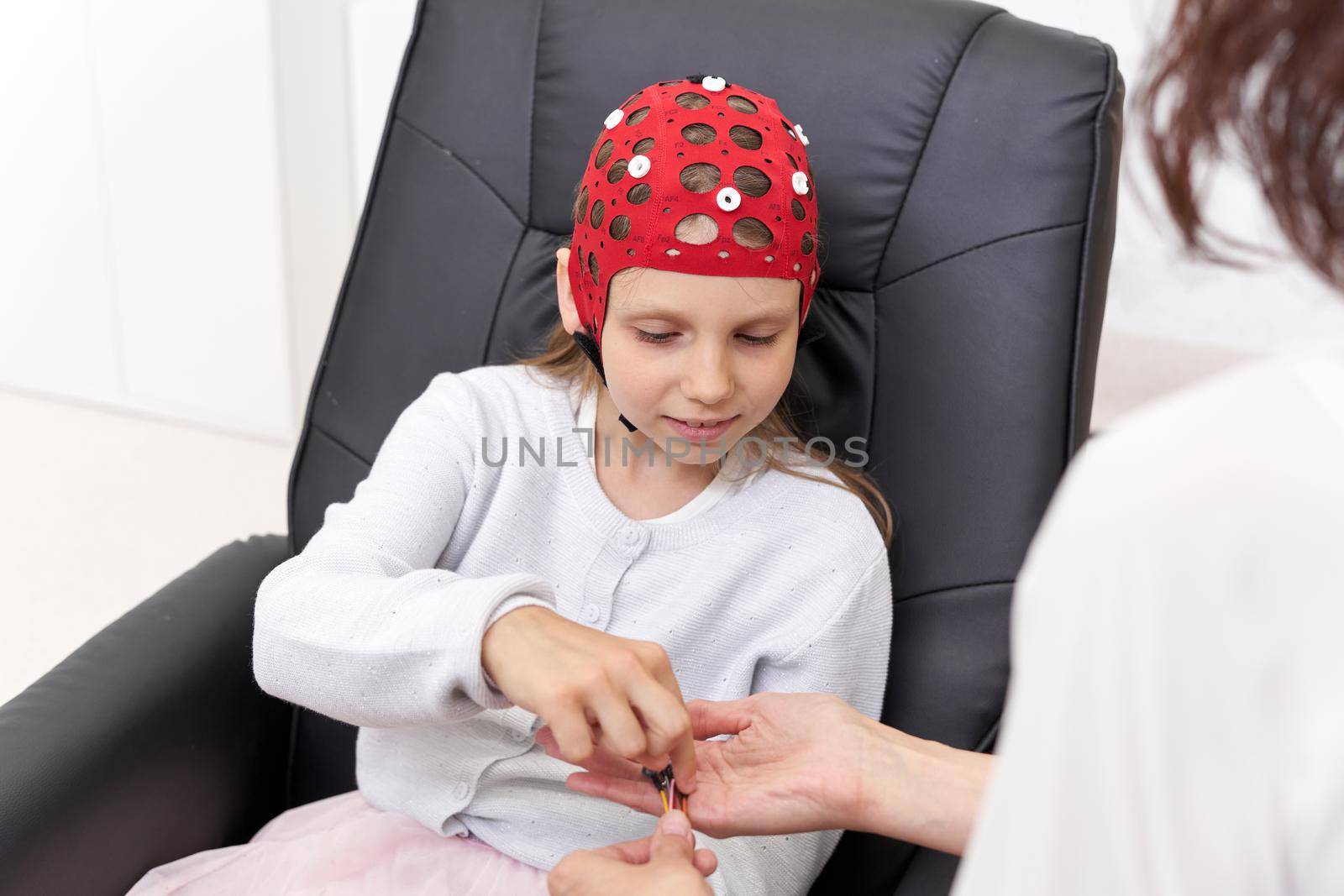 Girl taking electrodes from a doctor's hand in a biofeedback therapy in a clinic
