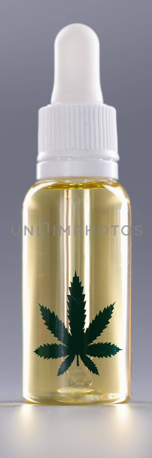 Closeup of bottle of marijuana oil on gray background. Hemp cosmetics concept