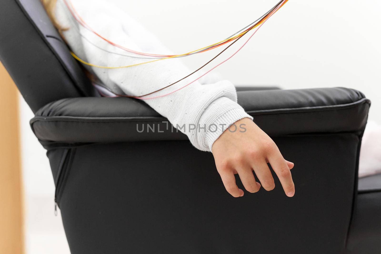 Cropped photo of the relaxed arm of a girl sitting in a chair during a biofeedback therapy session.