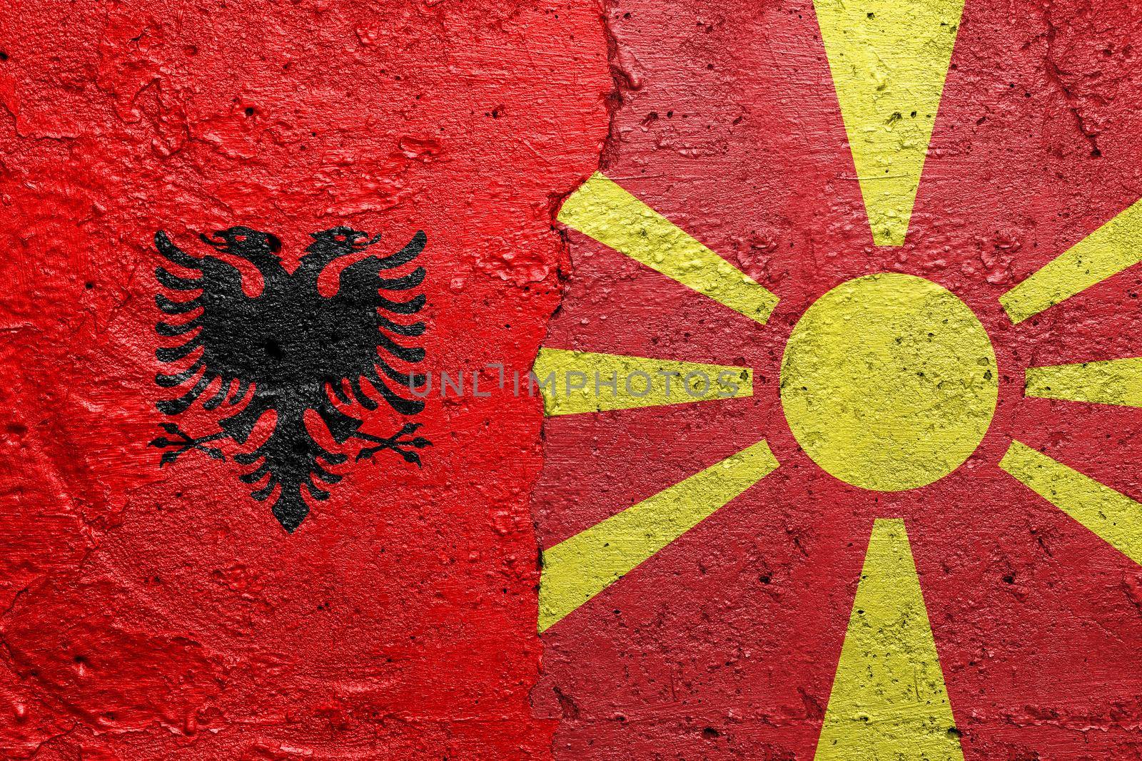 Bulgaria and North Macedonia - Cracked concrete wall painted with a Albanian flag on the left and a Macedonian flag on the right stock photo by adamr