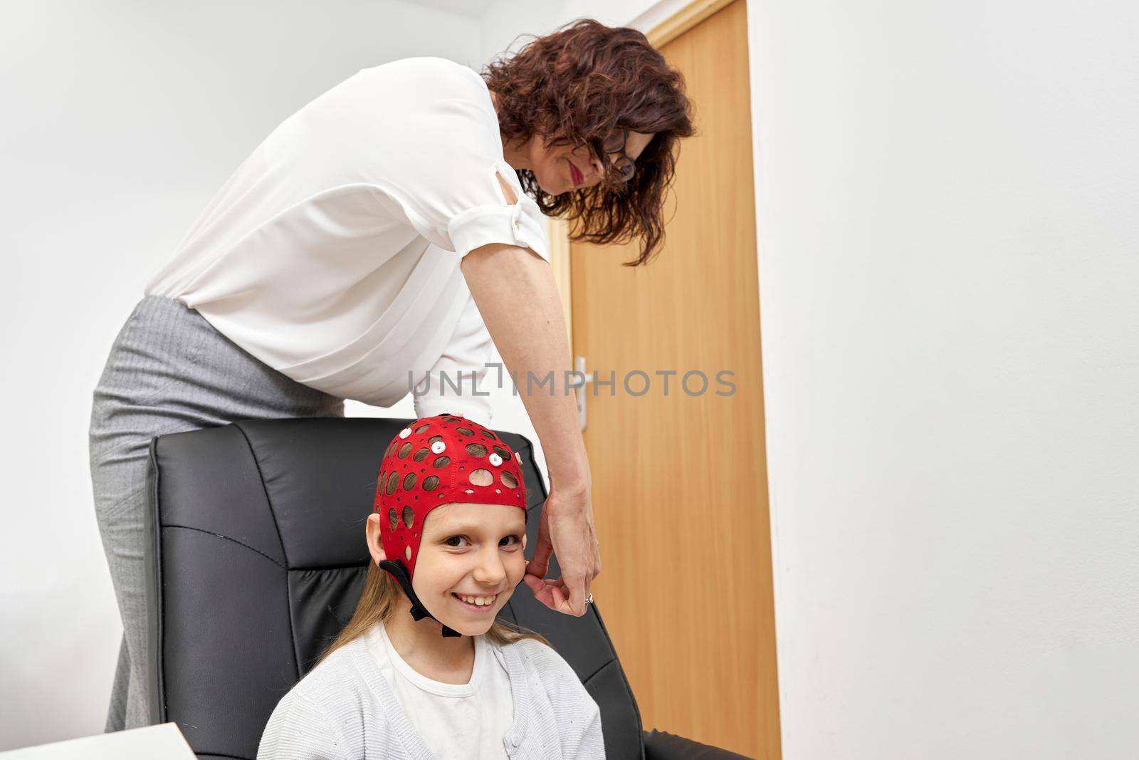 Girl smiling at camera as doctor prepares her for biofeedback session by WesternExoticStockers