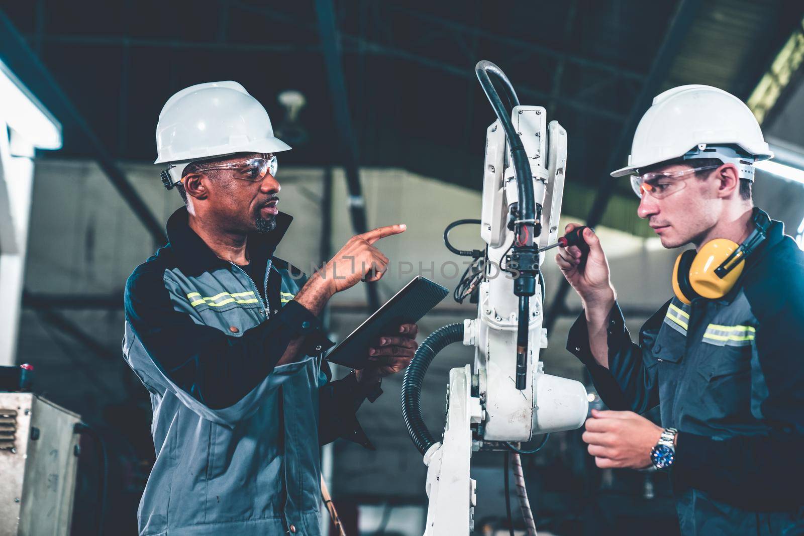 Factory workers working with adept robotic arm in a workshop . Industry robot programming software for automated manufacturing technology .