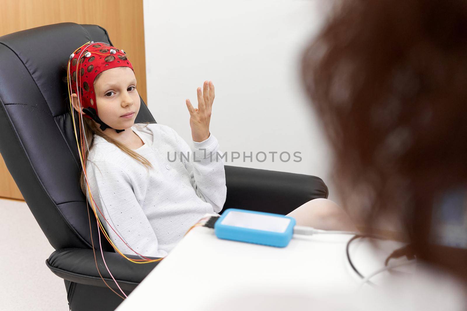 Young patient sitting on a chair raising the arm during a biofeedback session in a clinic