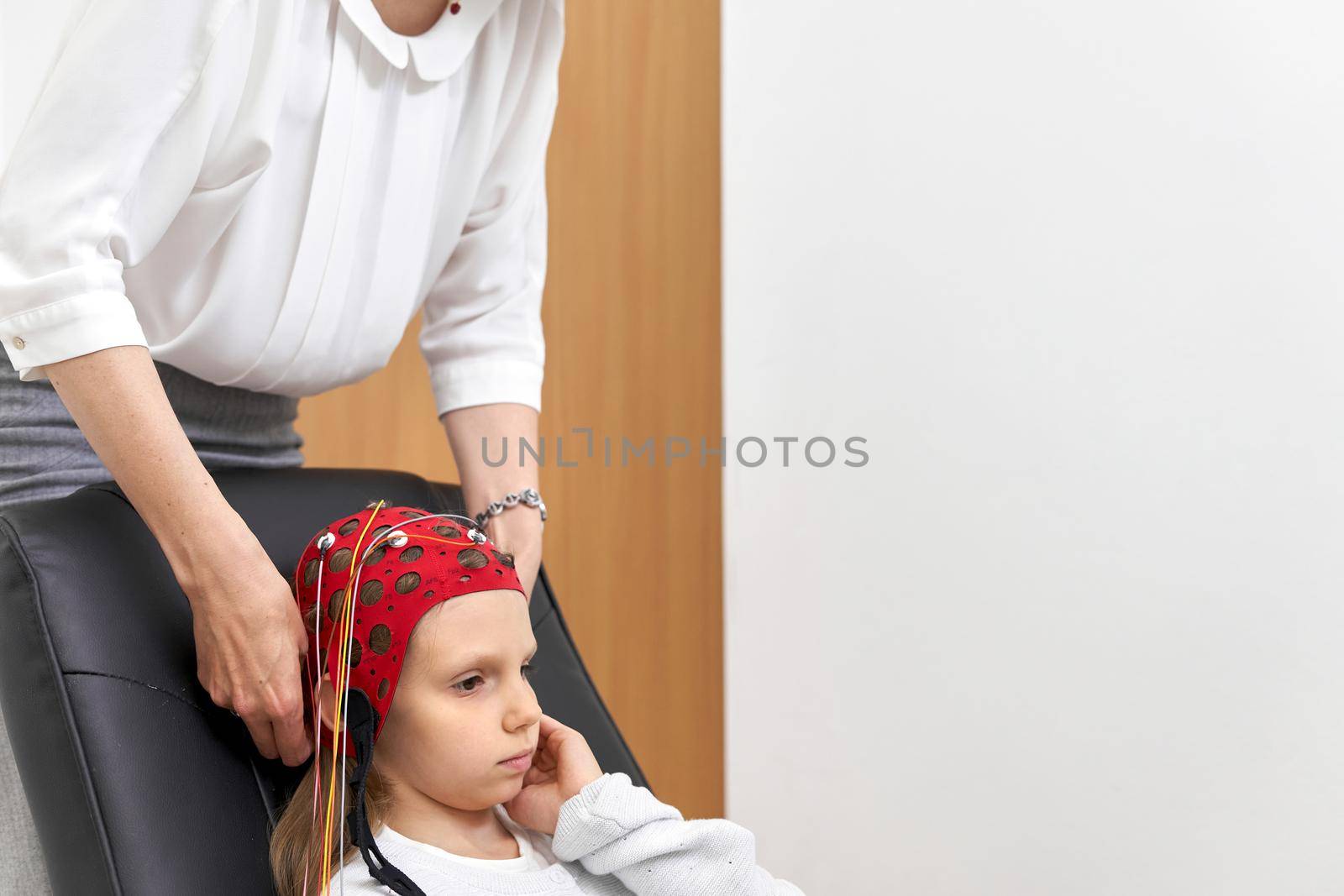 Doctor fixing the headgear to a patient during a biofeedback therapy by WesternExoticStockers