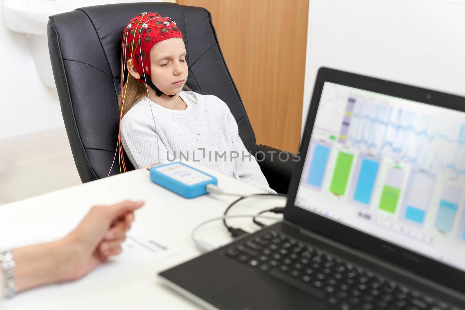 Young patient sitting in a chair during biofeedback therapy while being monitored by a doctor