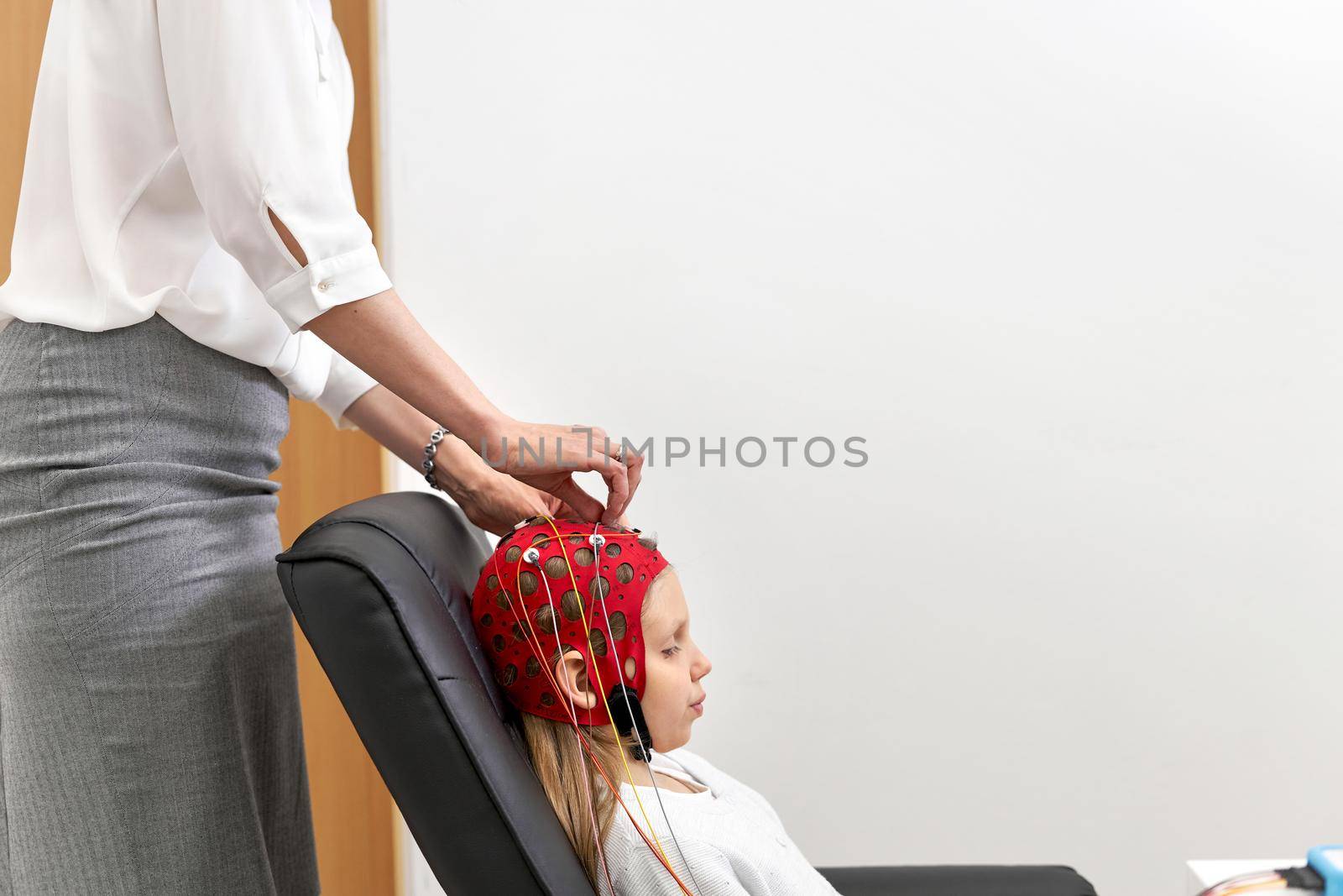 Profile of a doctor applying electrodes to a headgear of a patient during a biofeedback session