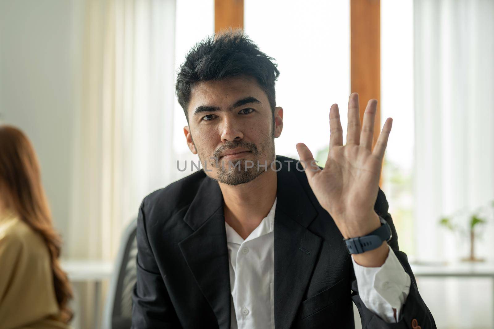 Webcam portrait of asian businessman looking directly at camera with friendly smile, waving hand, greeting gesture.