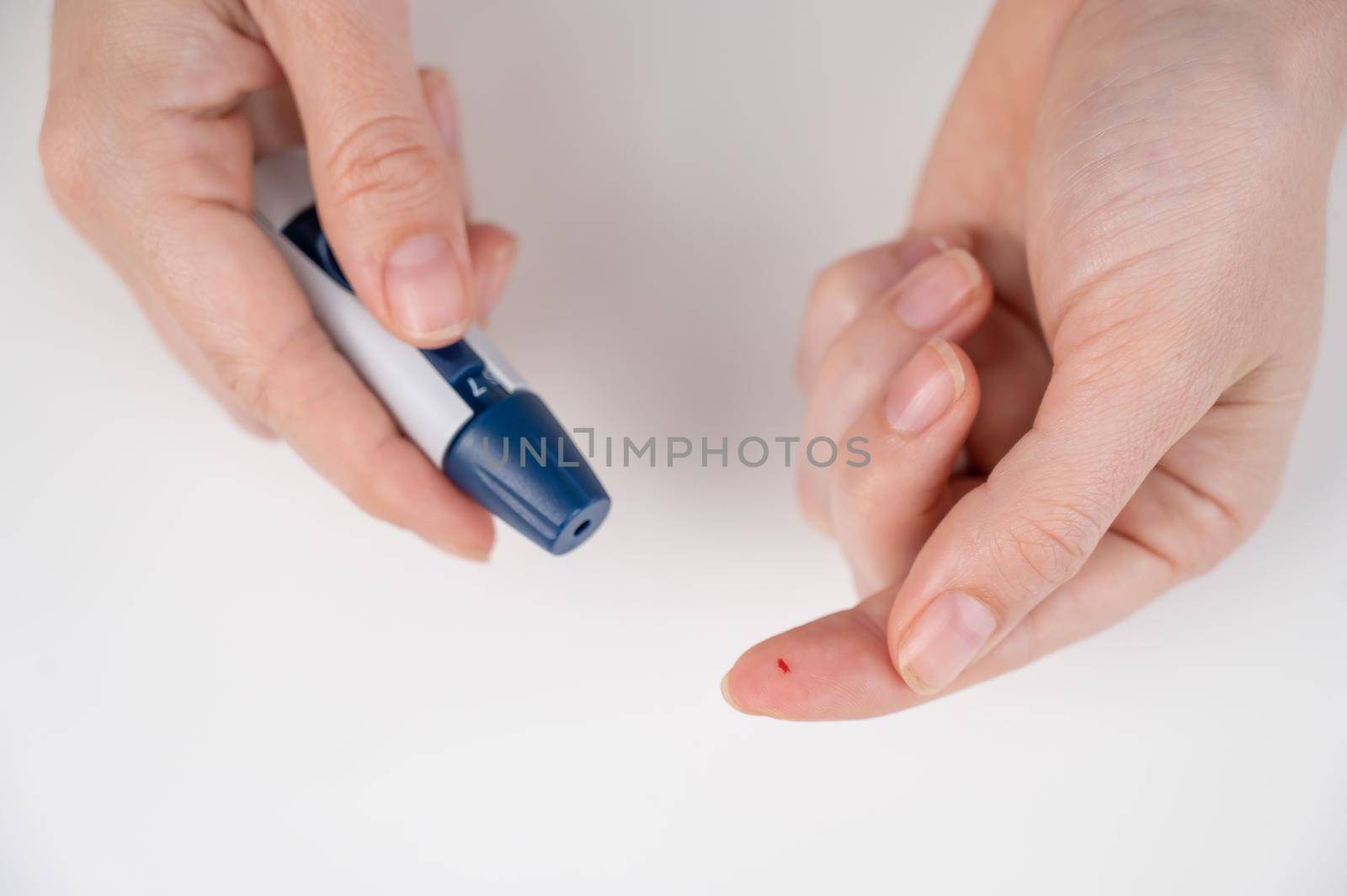 Caucasian woman doing a glucose test using a pen lancet