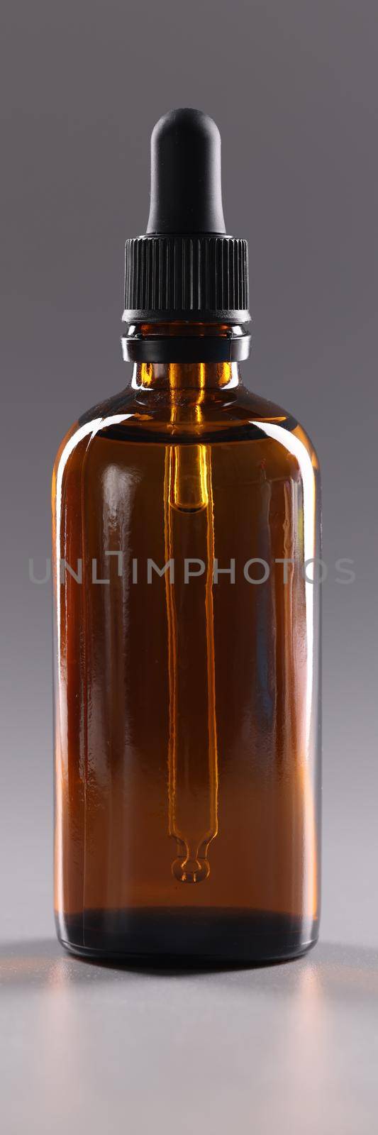 Closeup of glass bottle of cosmetic oil on gray background. Aromatherapy concept