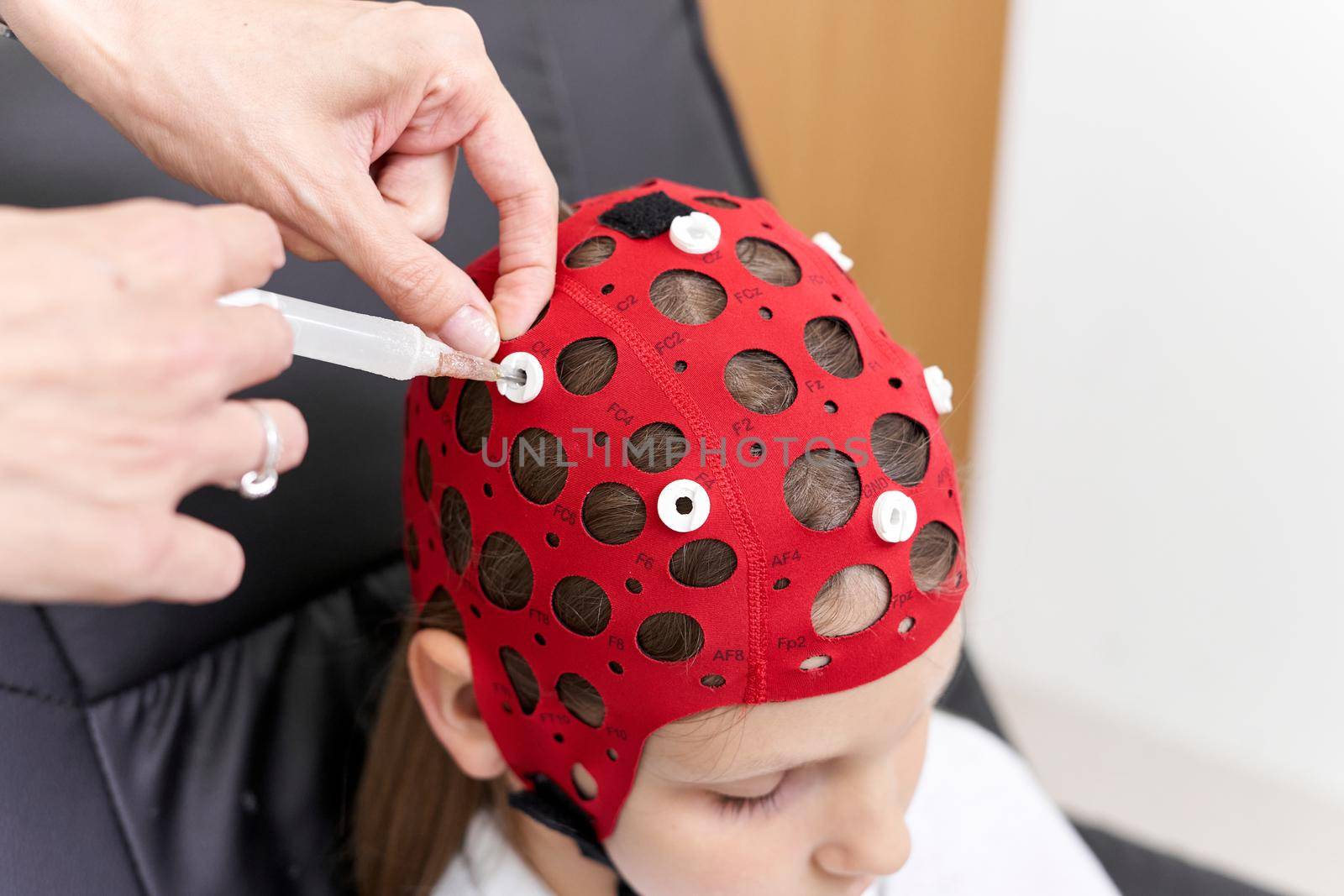 Top view of the hand of a doctor applying a liquid to a patient's headgear for biofeedback therapy.