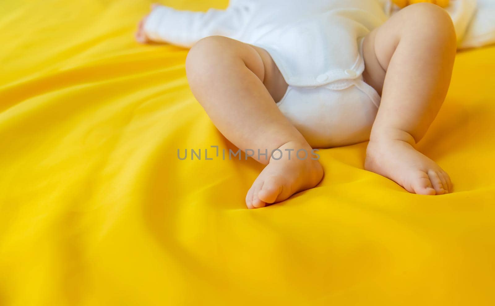 Baby feet on a yellow background. Selective focus. by yanadjana