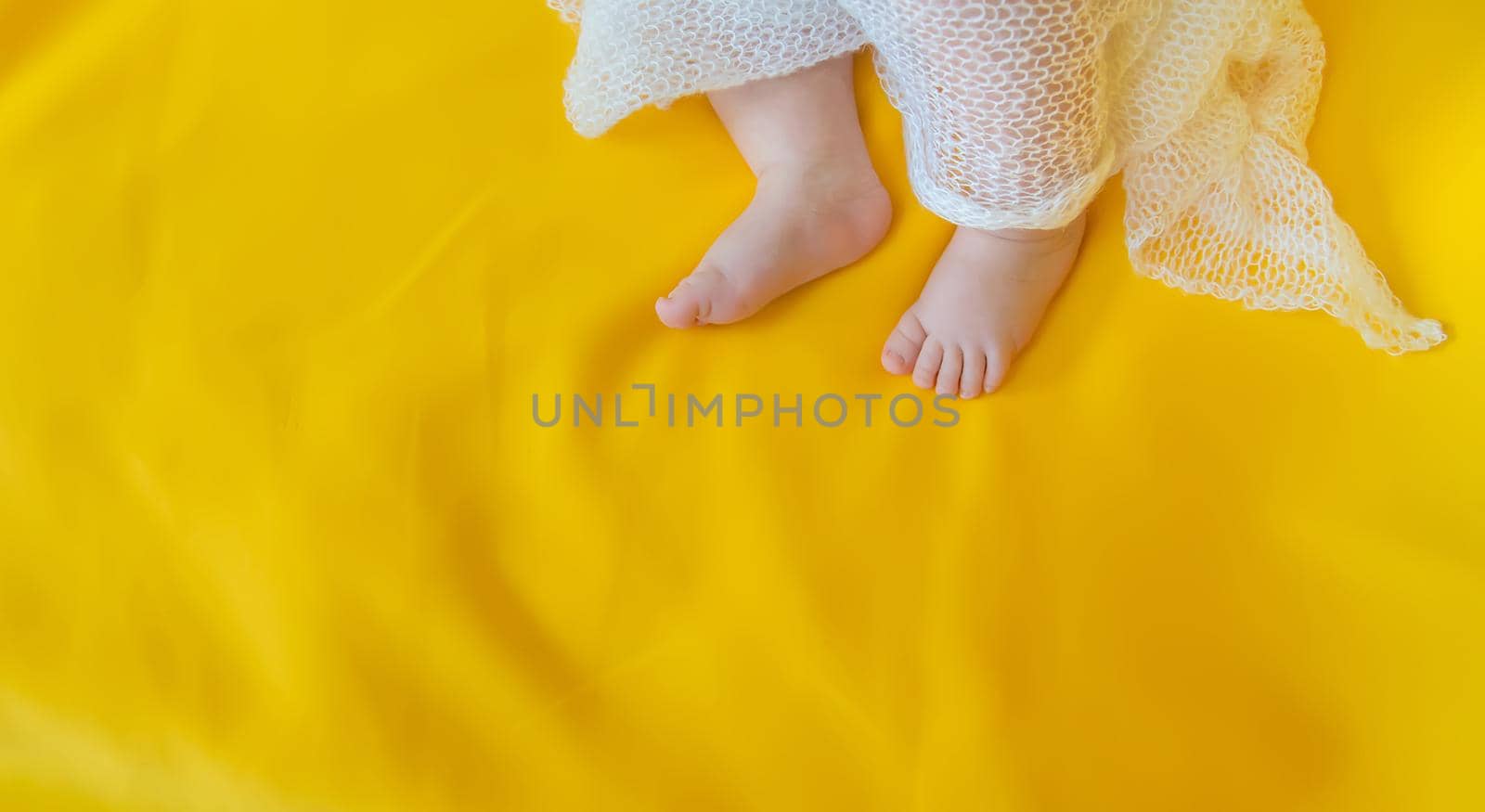 Baby feet on a yellow background. Selective focus. People. Merry Christmas and Happy New Year, Holidays greeting card background. Selective focus.