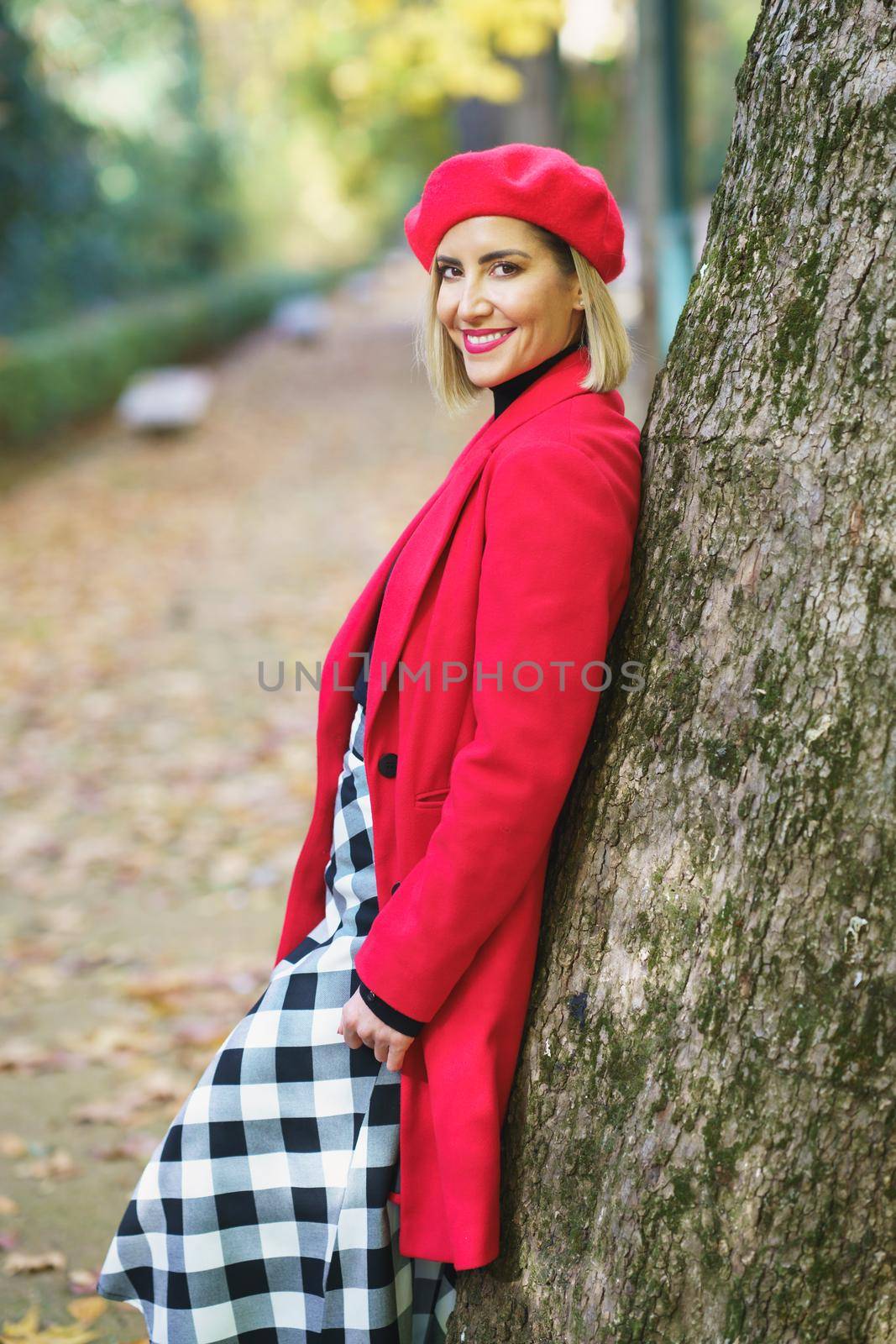 Charming woman standing near tree trunk in park by javiindy