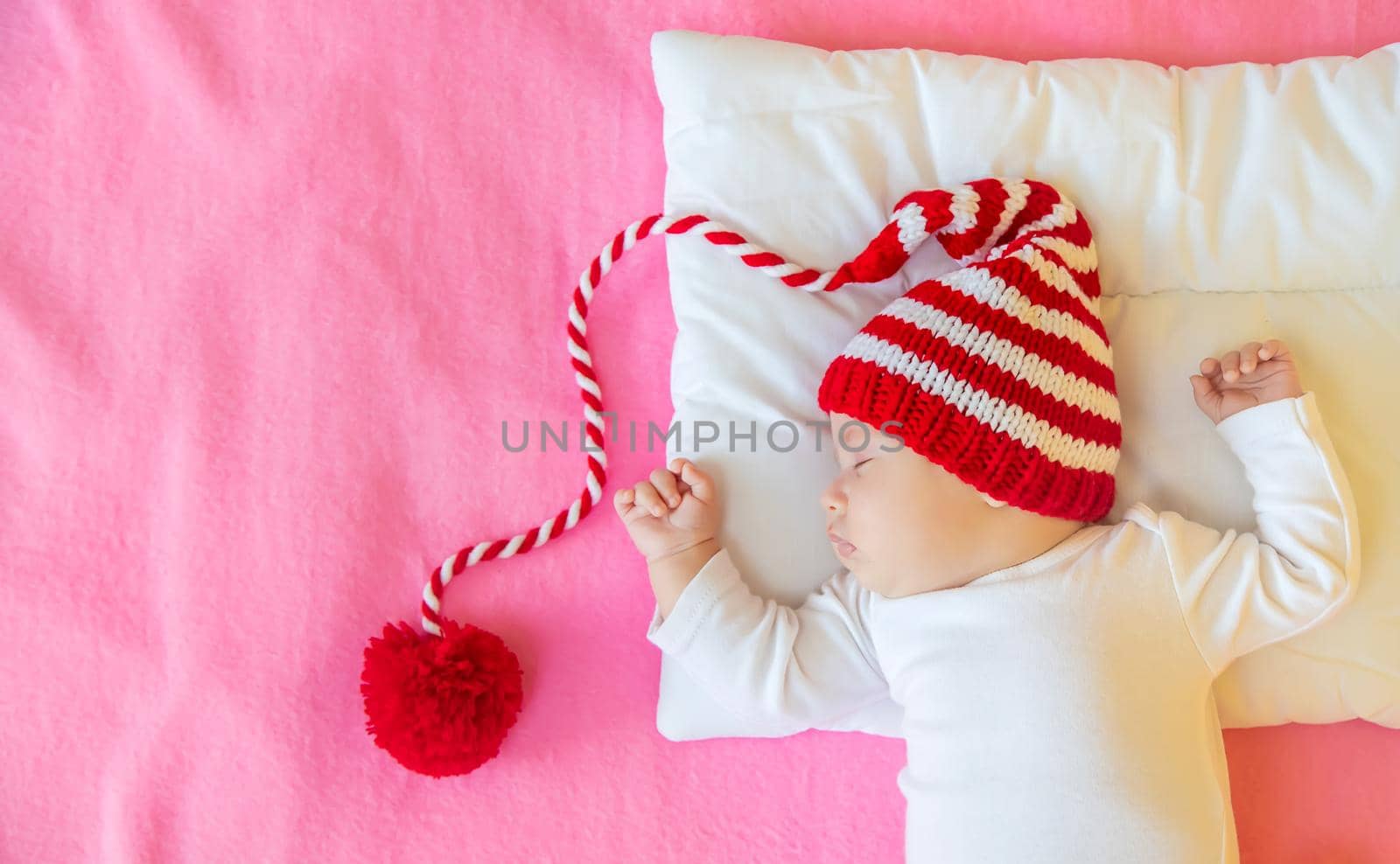 Baby sleeps in a Santa hat. Selective focus. People. Merry Christmas and Happy New Year, Holidays greeting card background. Selective focus.