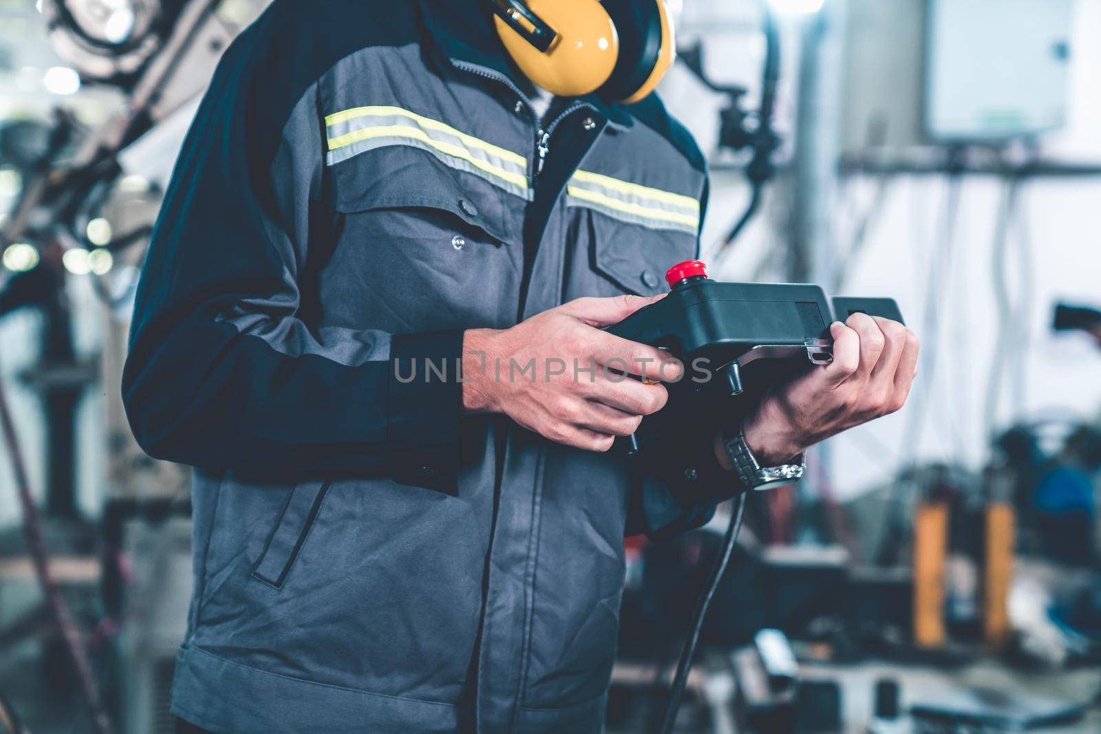 Young factory worker working with adept robotic arm in a workshop . Industry robot programming software for automated manufacturing technology .