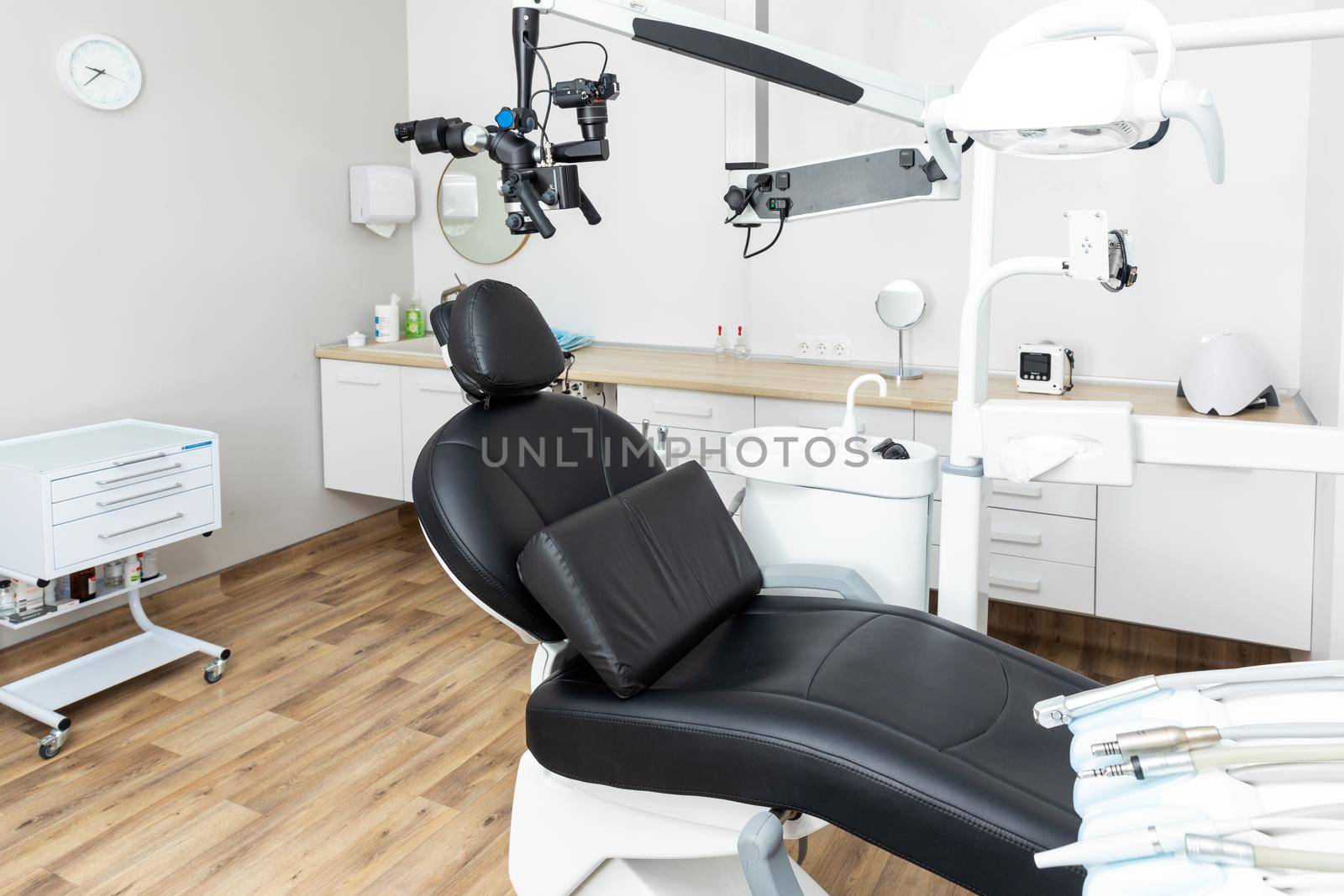 Modern dental cabinet in white colors. Defferent dental equipment, chair, lamp, drill machines. Concept dental treatment with microscope