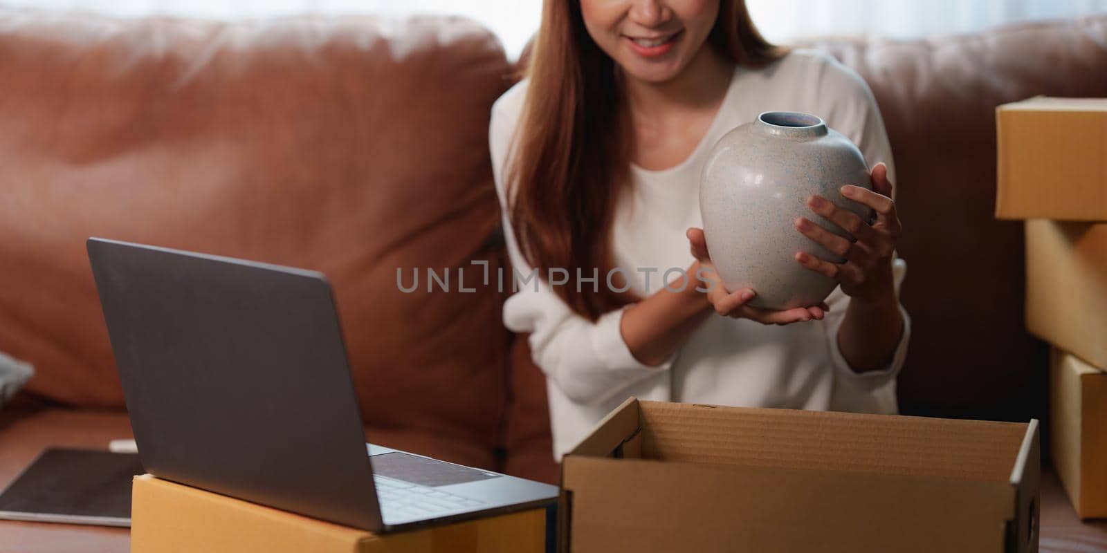 Image of Young asian woman startup freelance with parcel box and talking with customer by computer laptop. Online marketing packing box delivery concept