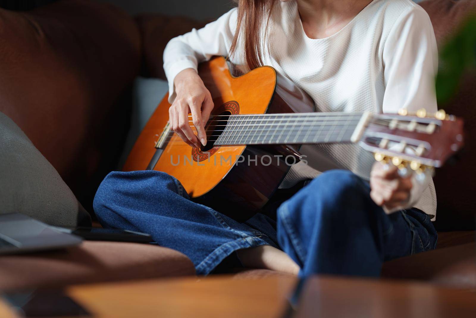 A beginner woman playing acoustic guitar lesson