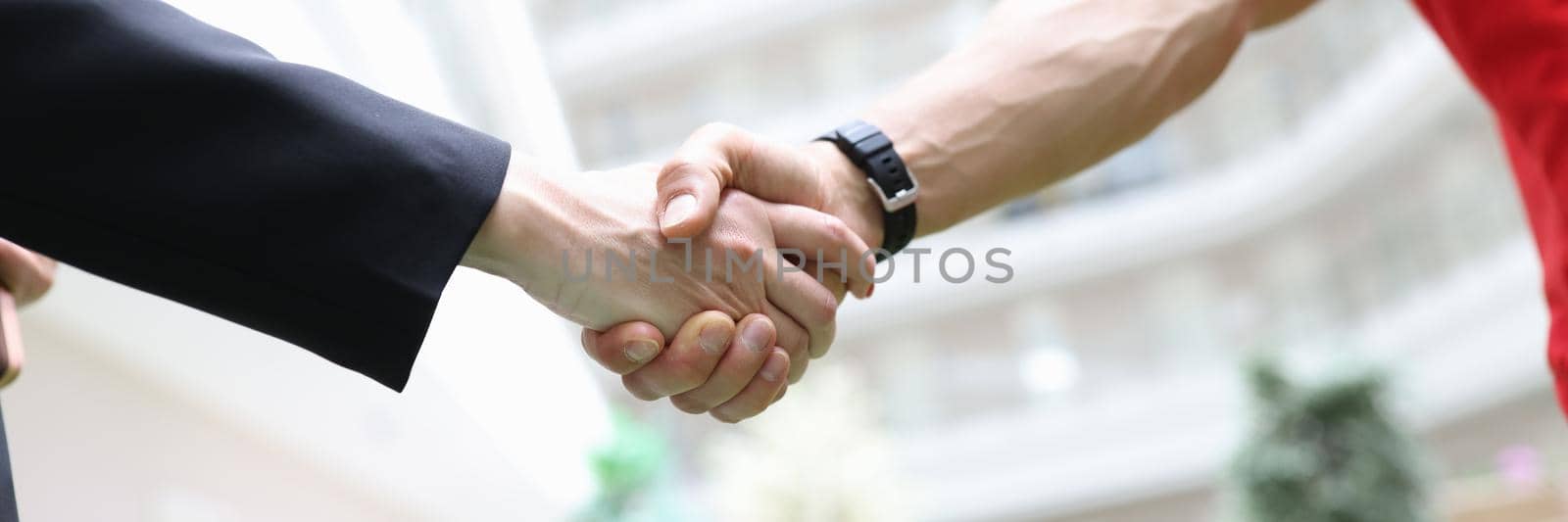 Handshake businessman and men in a red T-shirt, close-up. Freelancer, cooperation agreement. Promotion