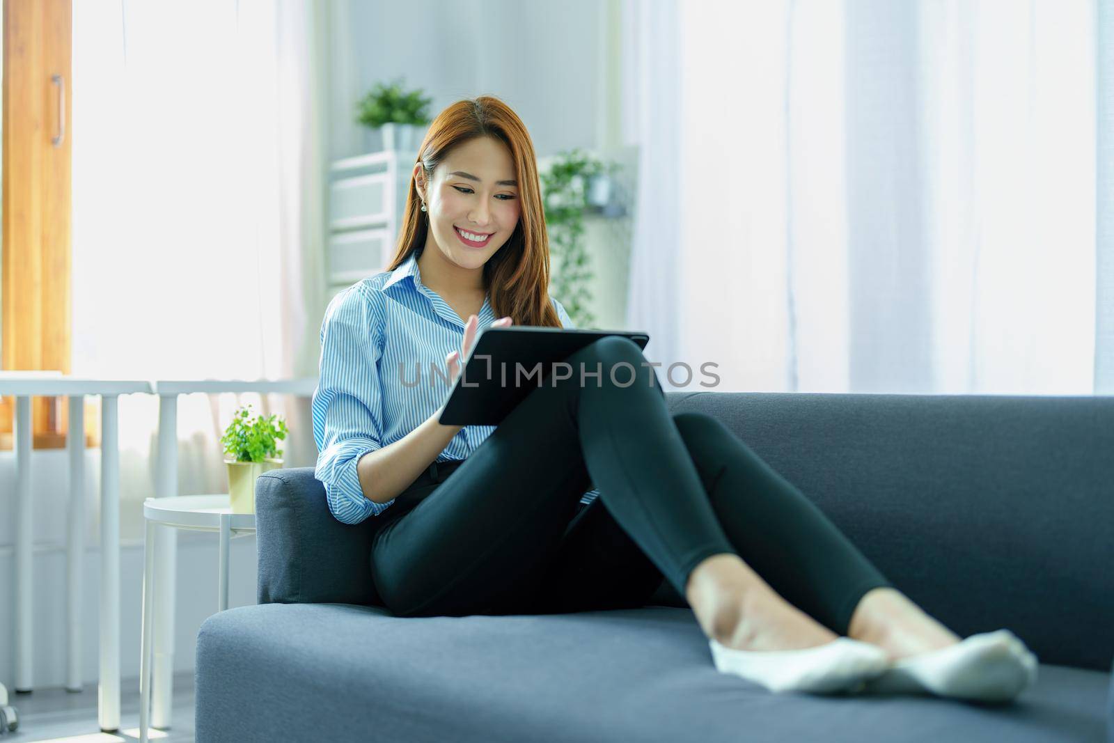 internet learning, online shopping, selling, meeting, information searching, young Asian woman using tablet mobile to work at home. by Manastrong