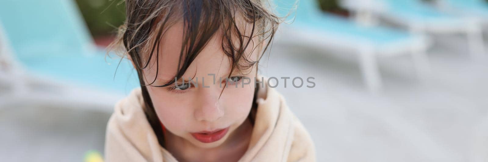 Wet frozen child by the pool, covered with a towel by kuprevich