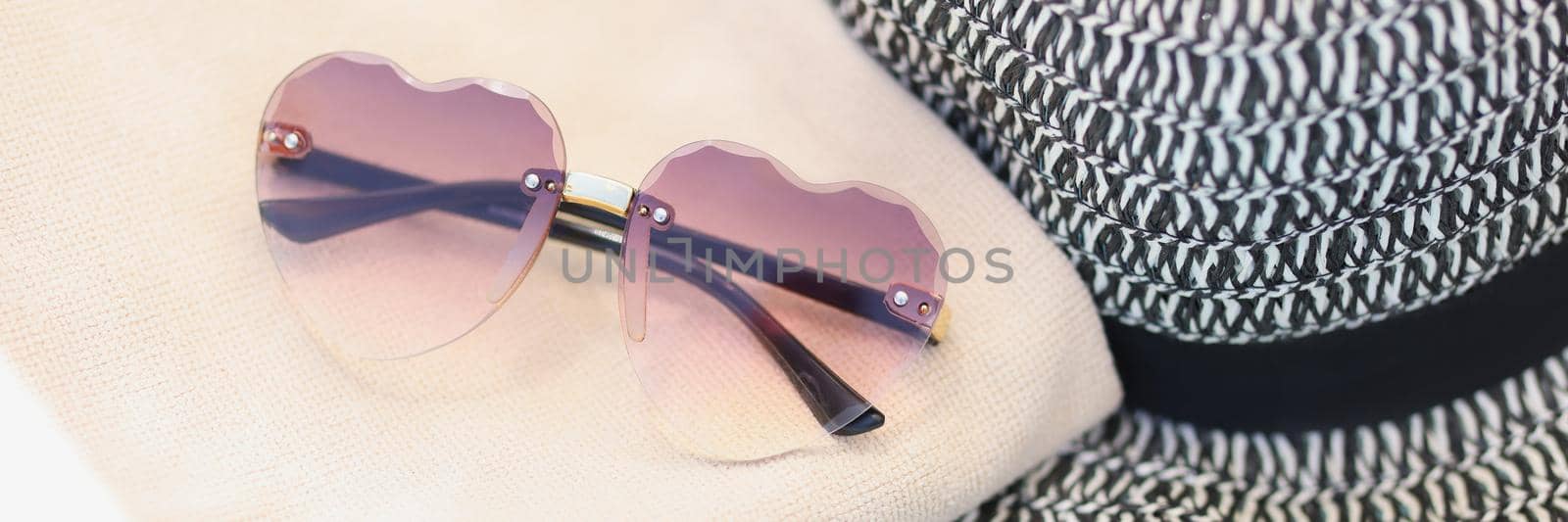 Sunglasses and a straw hat lie on a towel, close-up. Beach accessories, sun protection, vintage style