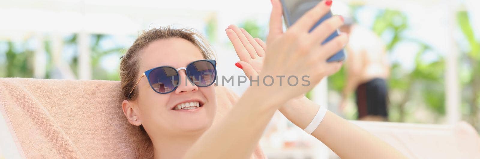 Happy woman in a swimsuit makes a selfie, close-up. Photo on vacation by the pool, summer vacation in the hotel complex