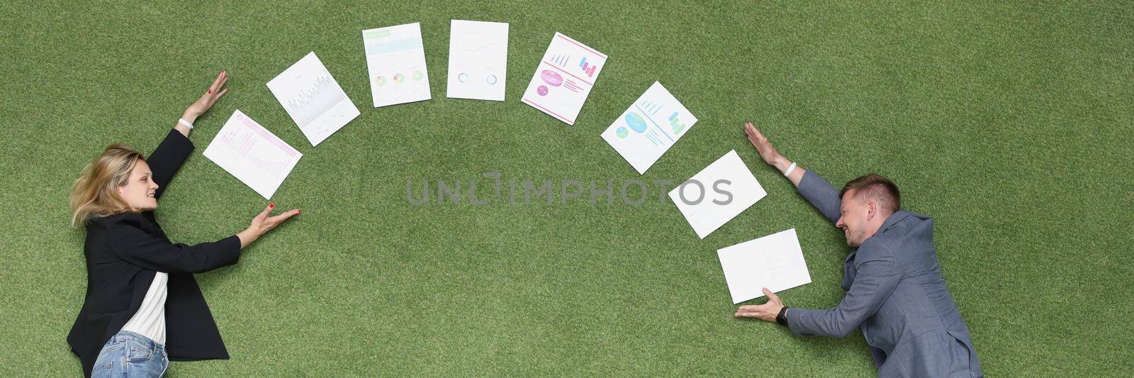 Between a man and a woman documents in a semicircle on a green cover, close-up, top view. Freelance collaboration, team concept