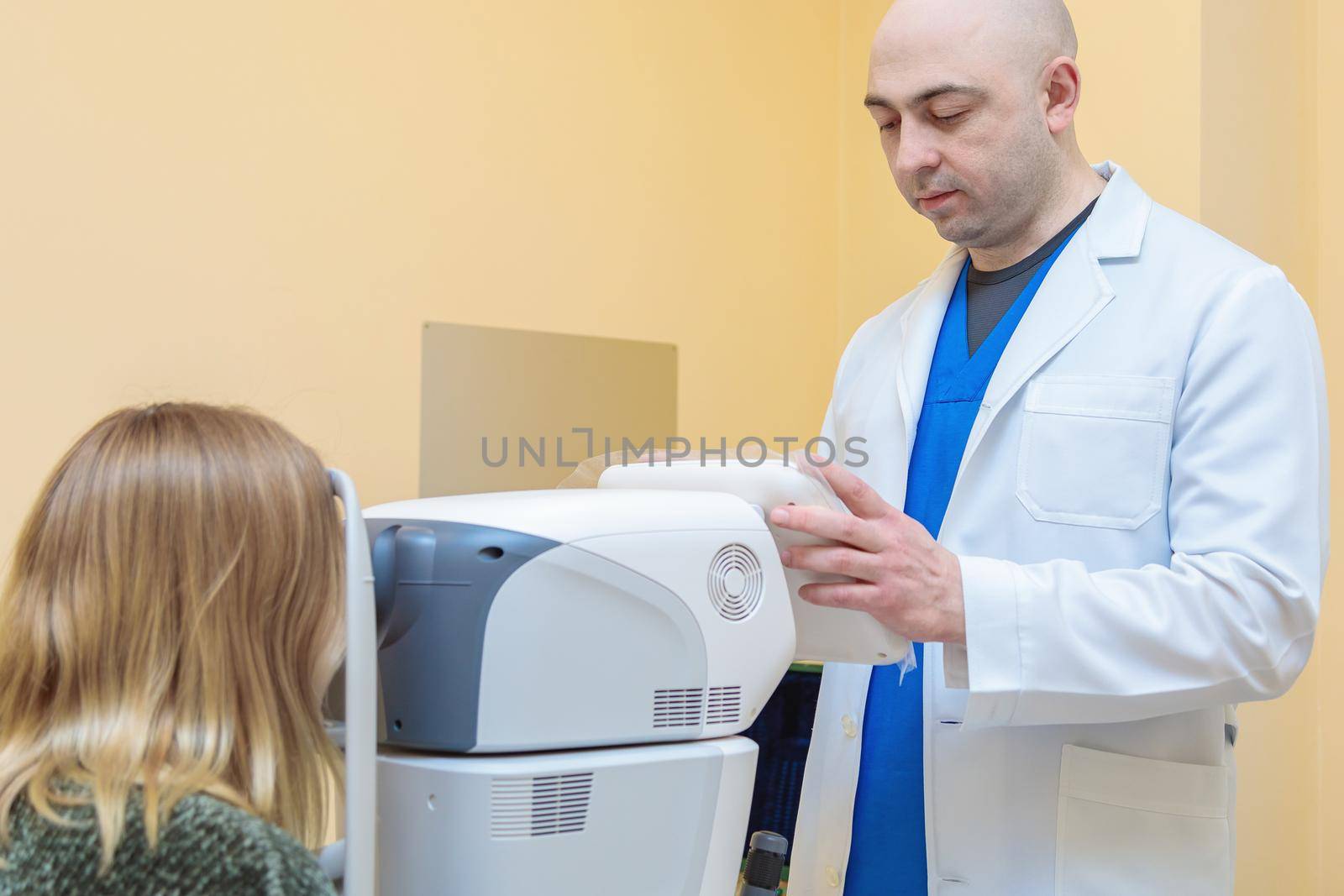 A male ophthalmologist checks the eyesight of a young girl using a modern vision tester.