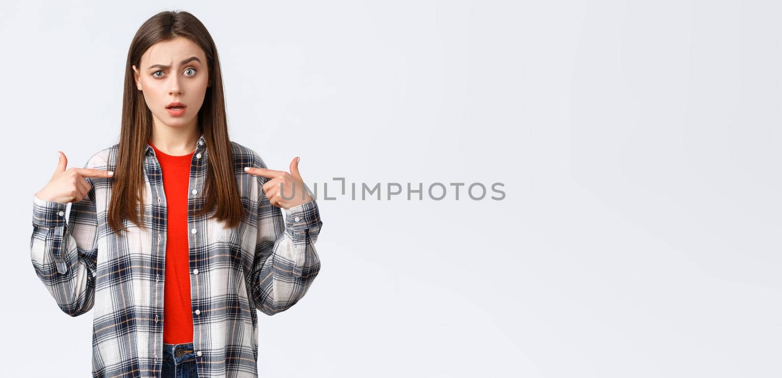 Lifestyle, different emotions, leisure activities concept. Confused young girl cant understand why she. Puzzled woman pointing at herself with raised eyebrow, being chosen, white background.