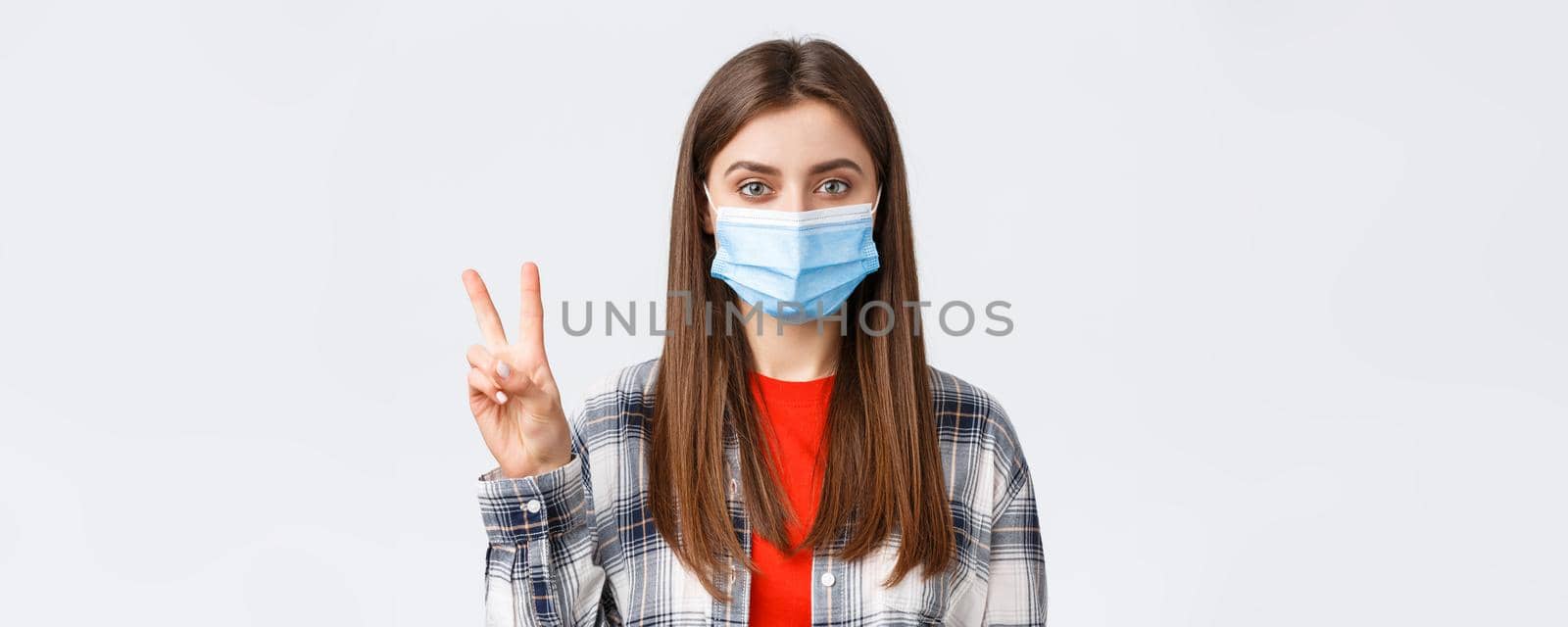 Coronavirus outbreak, leisure on quarantine, social distancing and emotions concept. Close-up of cute caucasian woman in medical mask making order, reservation for two, show number.