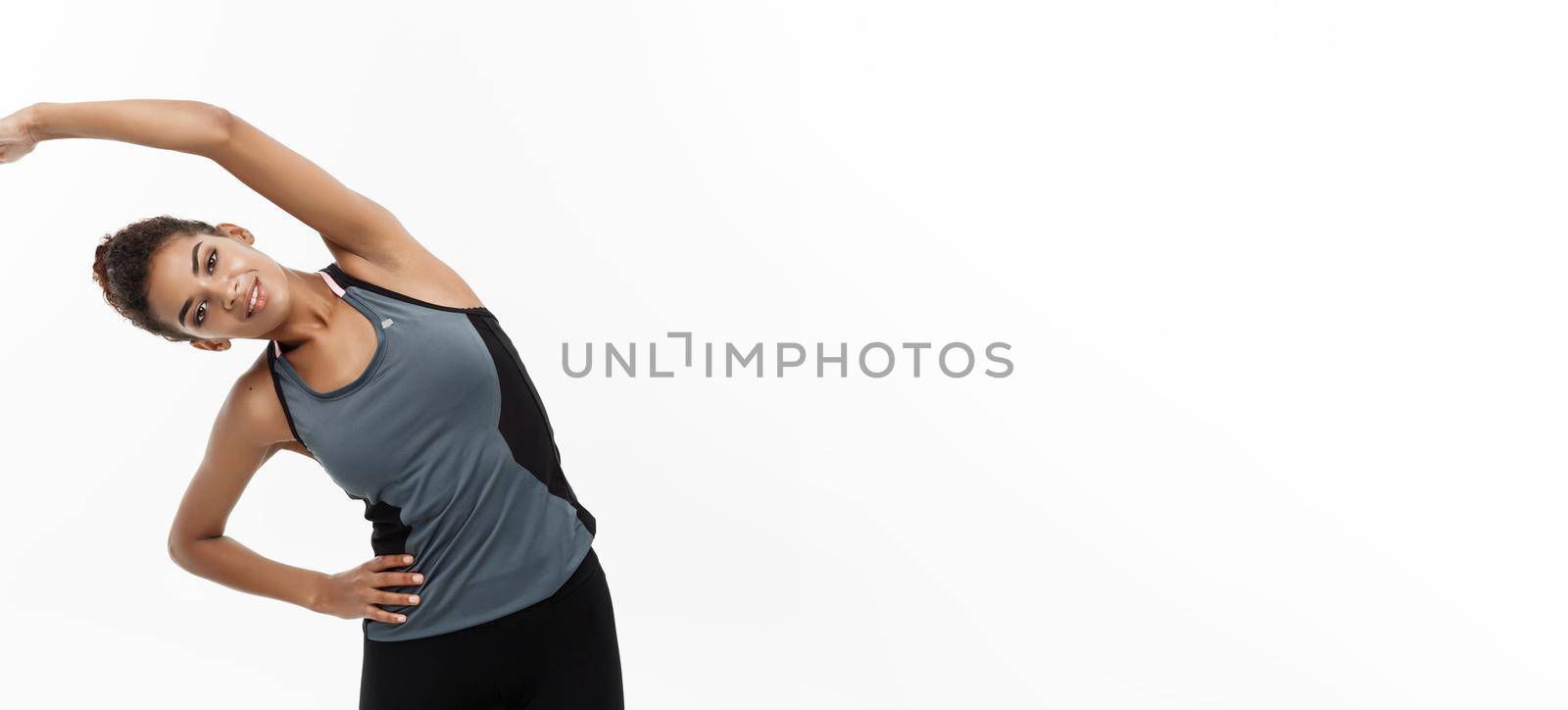 Sport, training, lifestyle and Fitness concept - portrait of beautiful happy African American woman stretching hands. Isolated on white studio background. by Benzoix