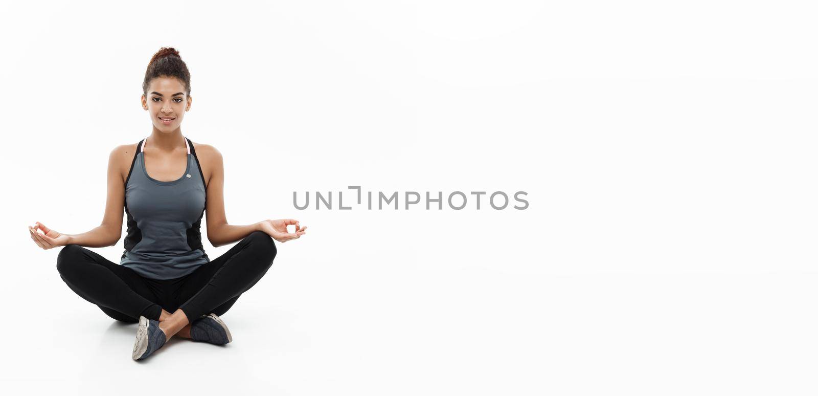 Healthy and Fitness concept - Beautiful American African lady in fitness clothing doing yoga and meditation. Isolated on white background. by Benzoix