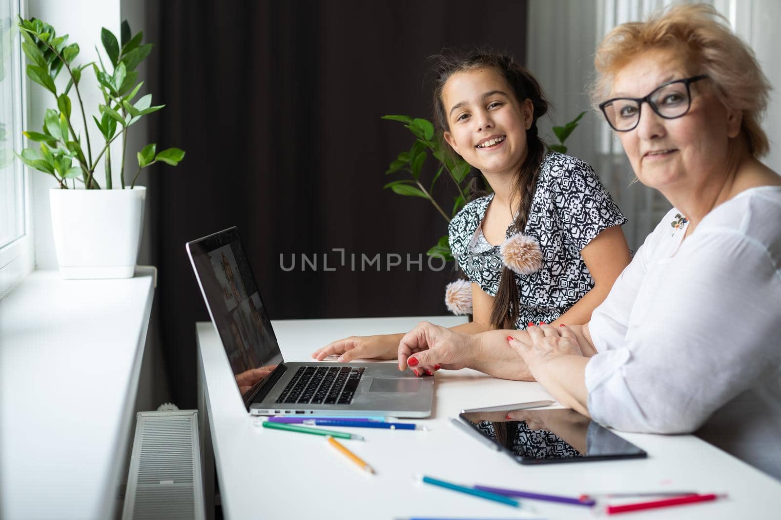 Happy grandmother and her granddaughter having video chat via laptop together at home