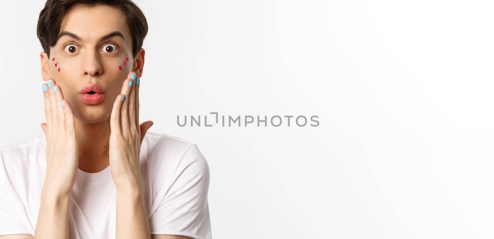 People, lgbtq and beauty concept. Close-up of handsome gay man express surprise, showing hands with blue nail polish, standing over white background by Benzoix