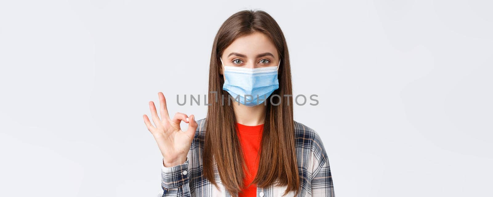 Coronavirus outbreak, leisure on quarantine, social distancing and emotions concept. Close-up of satisfied good-looking woman in medical mask, assure all good, show okay guarantee gesture.