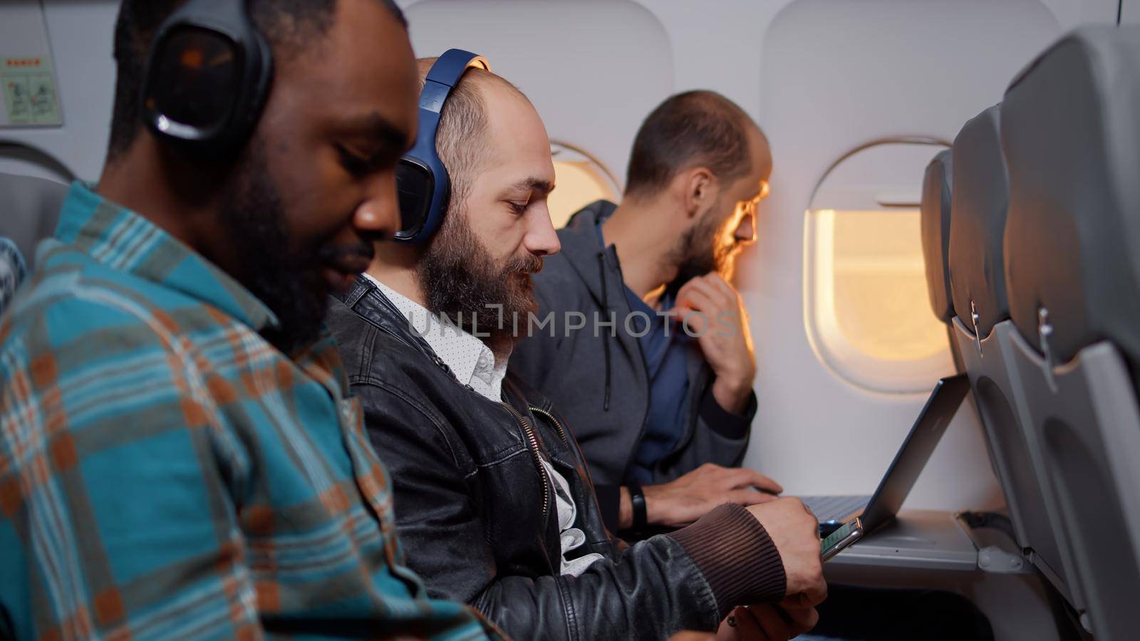 Entrepreneur browsing internet on smartphone during flight, travelling by airplane transportation on work trip. Flying with international airline using mobile phone during sunset.