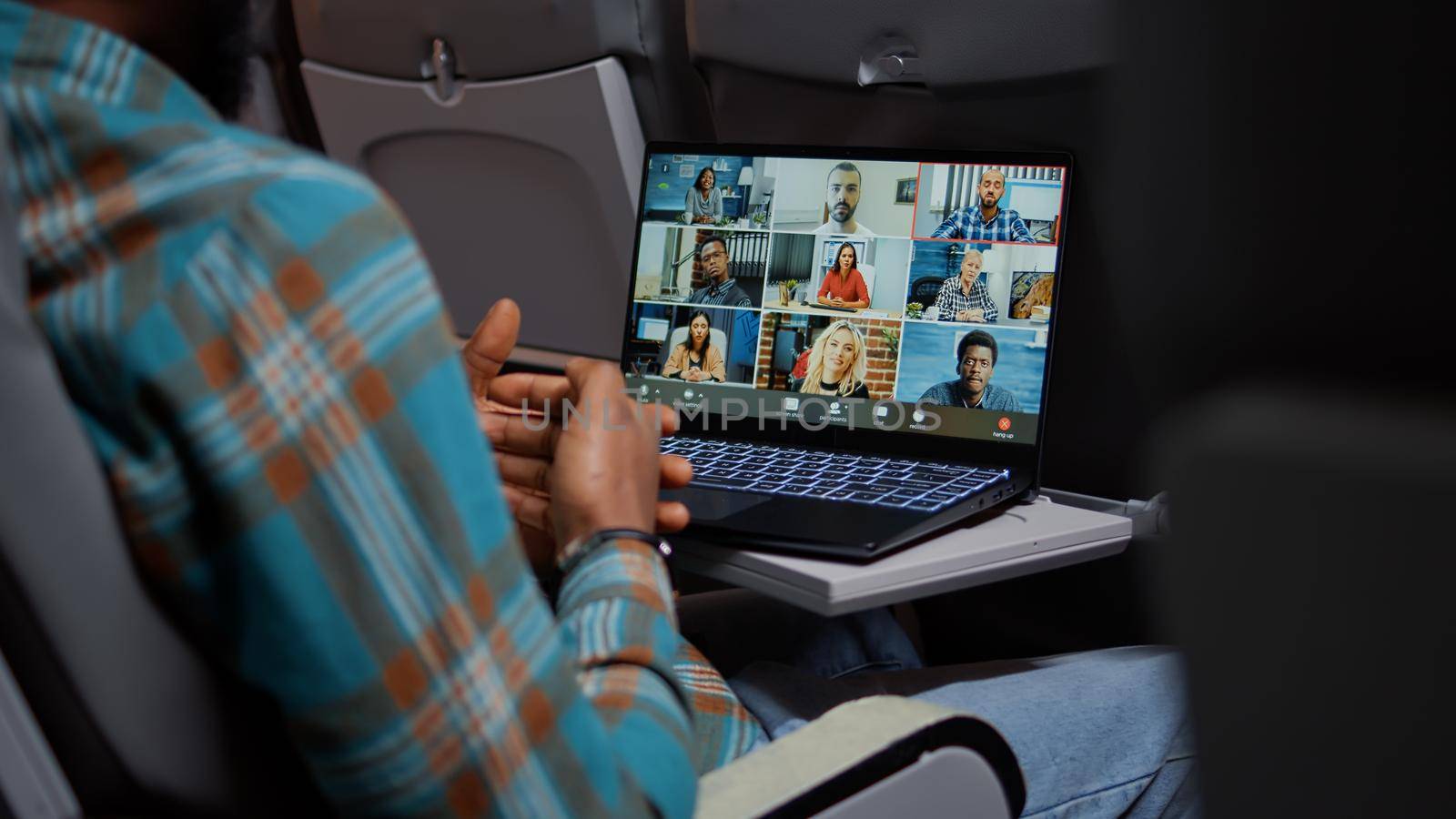 Entrepreneur in airplane attending online videocall meeting by DCStudio