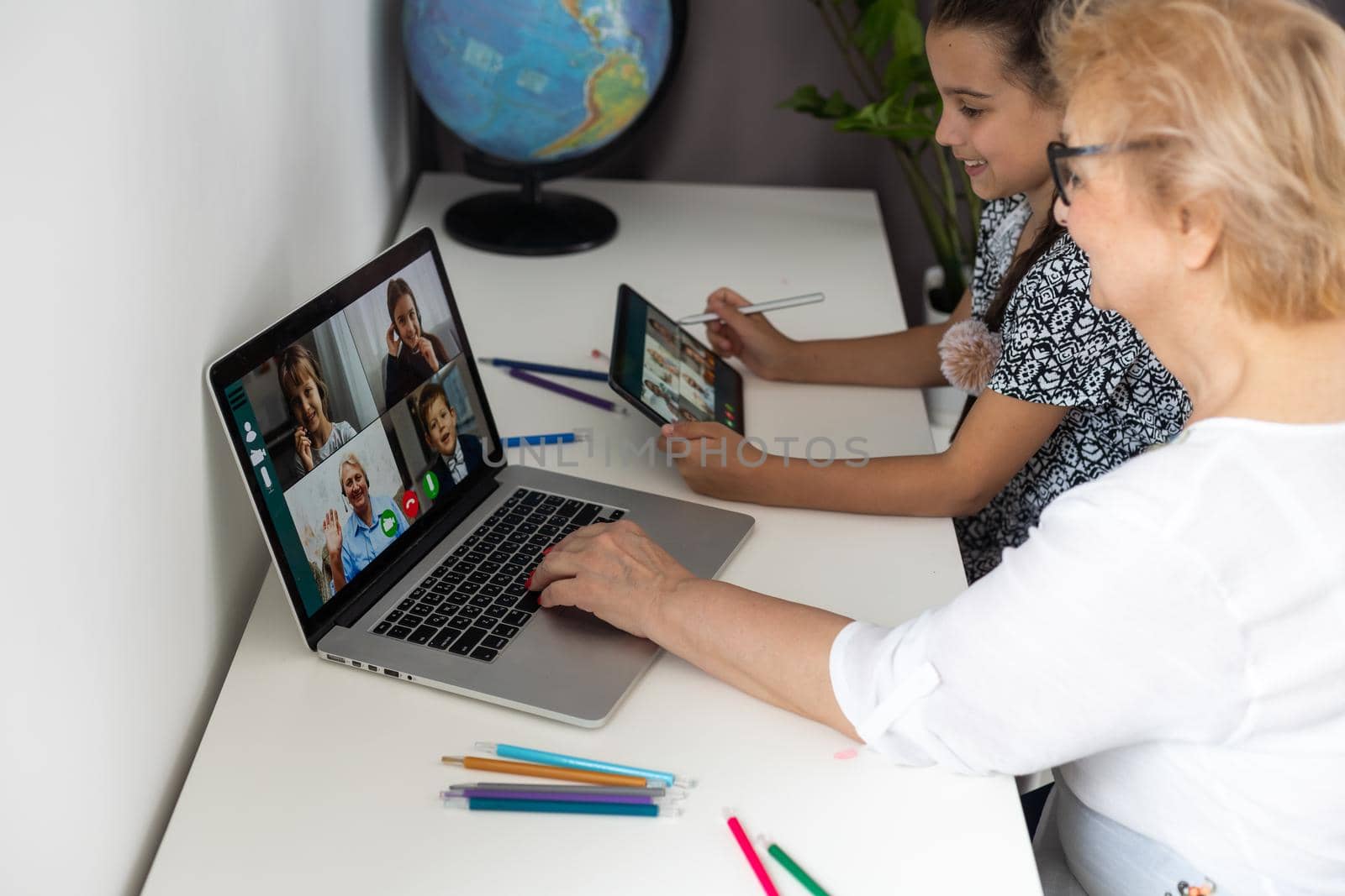 Grandmother and granddaughter using tablet and laptop